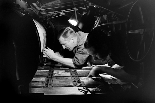 Man bending over a 1930s printer 